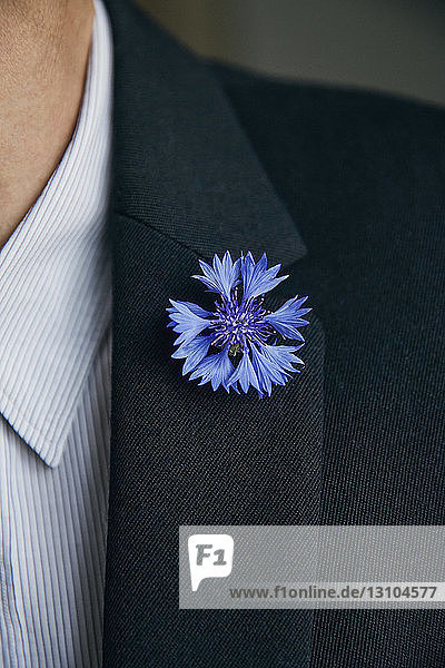 Blaue Blumennadel am Revers eines Mannes