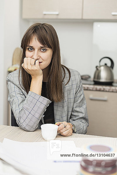 Portrait of woman sitting in kitchen