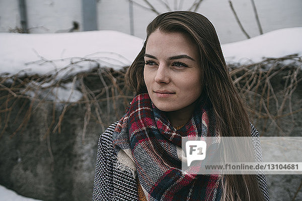 Thoughtful young woman in plaid scarf looking away