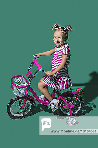 Portrait smiling girl bike riding against green background