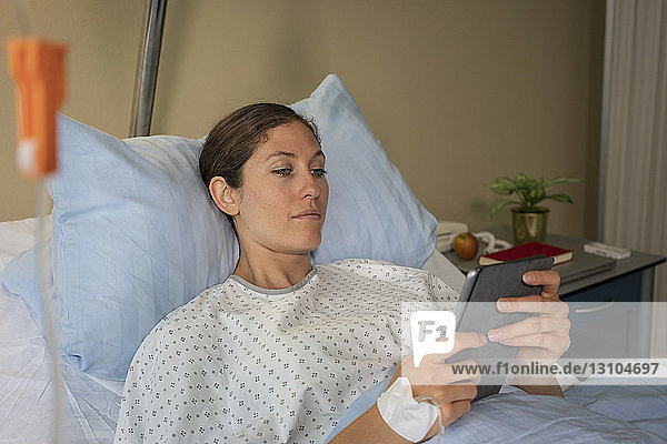 Weiblicher Patient mit digitalem Tablet  der sich im Krankenhausbett erholt