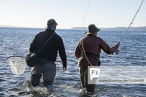A guide advises his client while fly fishing in salt water for searun coastal cutthroat trout and salmon in northwest Washington State  USA