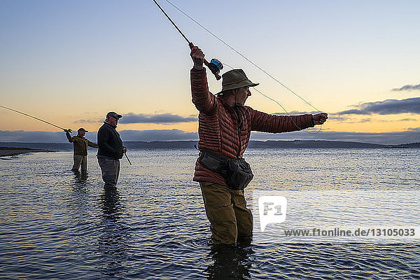 Zwei Fliegenfischer  die an einem Salzwasserstrand an einem Strand an der Westküste der USA mit ihrem Führer zwischen ihnen stehend  nach Searun-Cutthroat-Forellen und Lachsen werfen