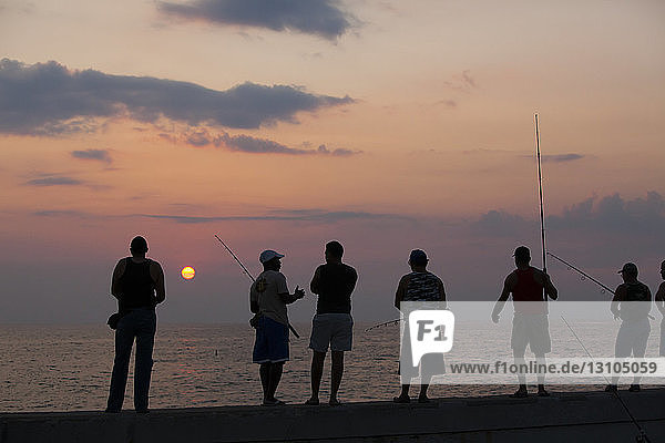Fischer versuchen ihr Glück und stehen auf dem Geländer der Malecon-Hafenmauer in Havanna  Kuba