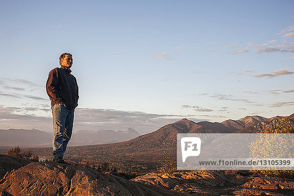 Mann betrachtet die Landschaft vom Gipfel der Butte  Lazy Mountain im Hintergrund an einem klaren  sonnigen Abend im Herbst  Süd-Zentral-Alaska; Palmer  Alaska  Vereinigte Staaten von Amerika