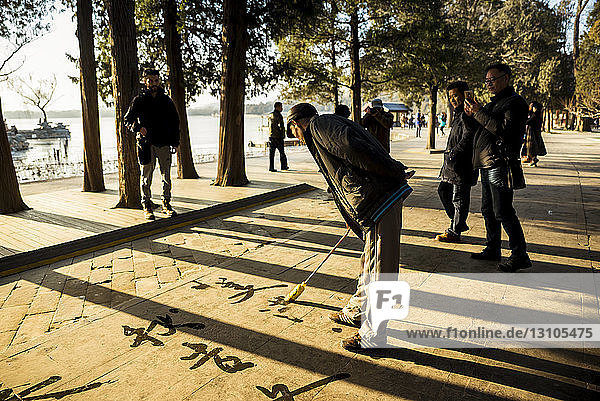 Mann schreibt übergroße Kalligrafie auf den Boden  Sommerpalast; Peking  China