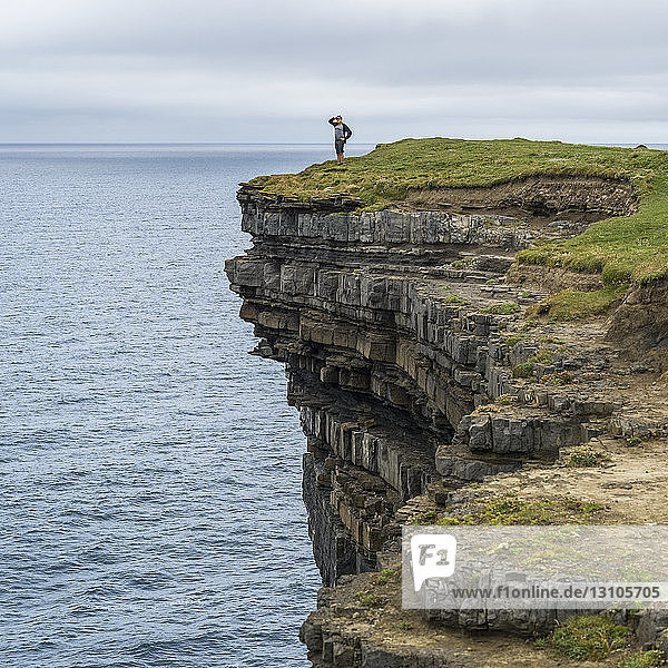 A male tourist stands looking out over the ocean from Downpatrick Head, West coast of Ireland; Killala, County Mayo, Ireland