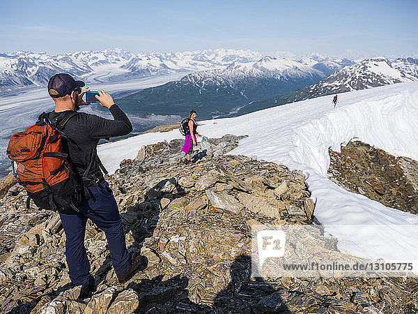 Taking photos with a cell phone on a mountaintop in Kluane National Park and Reserve; Haines Junction  Yukon  Canada