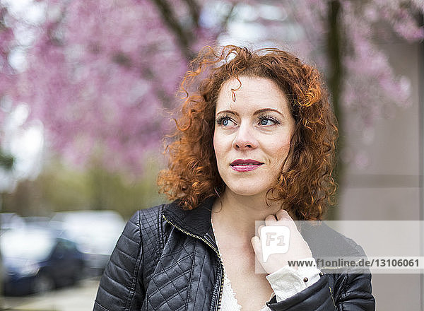 Porträt einer Frau mit rotem  lockigem Haar  die im Frühling im Freien spazieren geht; North Vancouver  British Columbia  Kanada