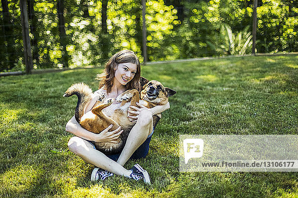 Teenage girl holding her dog on a grass field in a park; Surrey, British Columbia, Canada