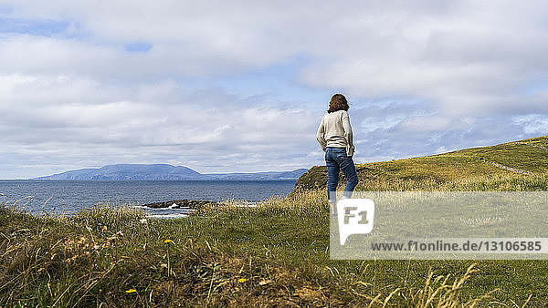 A woman stands looking out to the ocean and coastline  Mullaghmore peninsula; Grange  County Sligo  Ireland