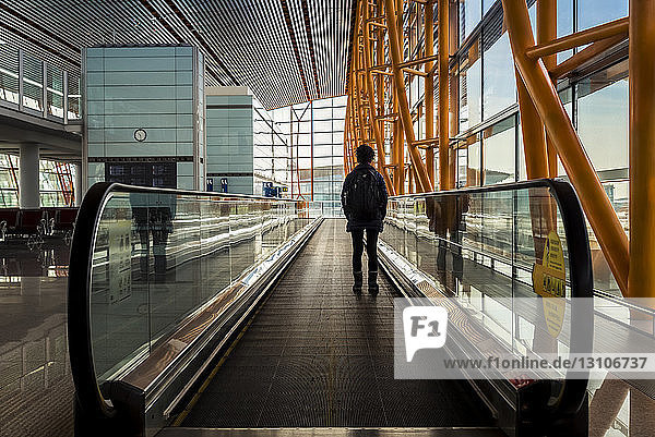 Passagier  der auf dem sich bewegenden Bürgersteig im Flughafen-Terminalgebäude steht  Internationaler Flughafen Peking; Peking  China