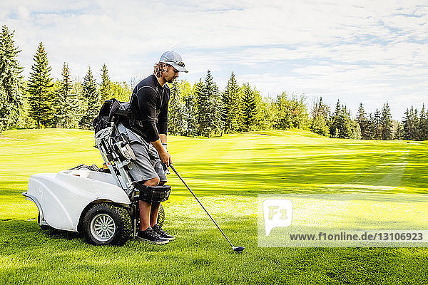 Ein körperlich behinderter Golfer  der einen Spezialrollstuhl benutzt  richtet seinen Driver auf dem Golfgrün auf den Ball aus; Edmonton  Alberta  Kanada