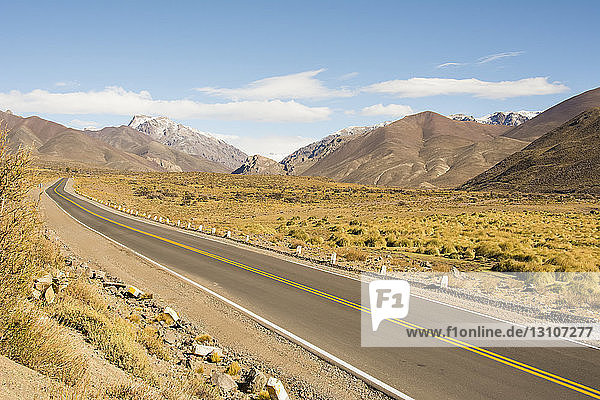 A road leads the eye through desert and snow-capped mountains; Malargue  Mendoza  Argentina