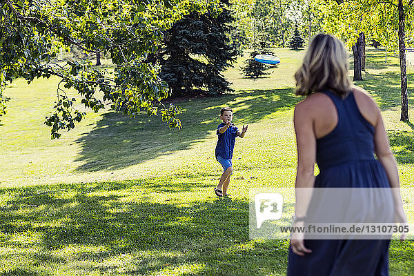 A mother throwing a disc toy to her son to catch in a park on warm fall afternoon during a family outing; Edmonton  Alberta  Canada