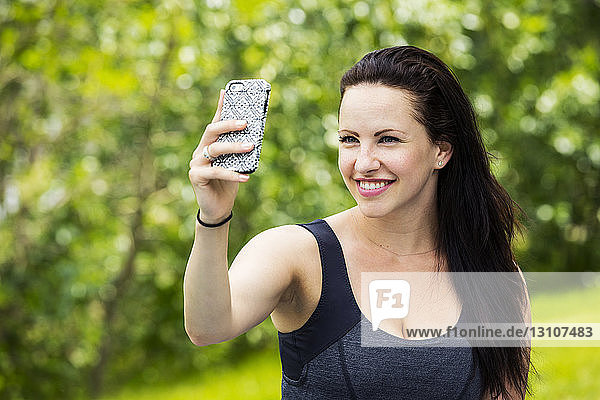 Beautiful young woman taking a self-portrait while enjoying the outdoors in a park; Edmonton  Alberta  Canada