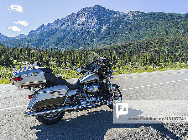 A motorcycle parked on the side of the road with view of the Rocky Mountains Jasper National Park; Alberta Canada