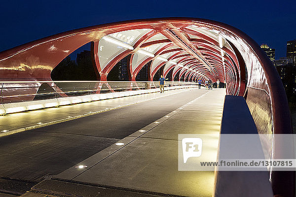 Glowing lights inside a pedestrian red metal bridge at night; Calgary Alberta Canada