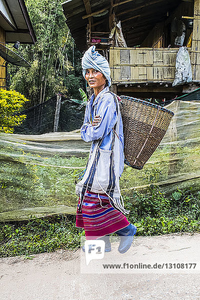Young woman from the Karen tribe wearing traditional garments in a village; Thailand