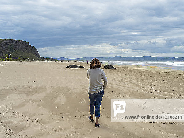 Woman walking on Downhill Beach  Northern Ireland; Castlerock  County Londonderry  Ireland