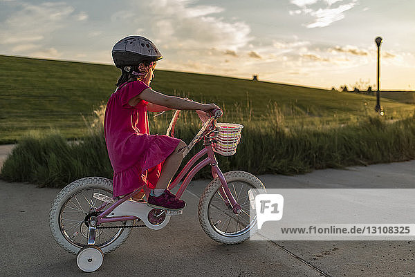 Seitenansicht eines Mädchens  das auf der Straße gegen den Himmel Fahrrad fahren lernt