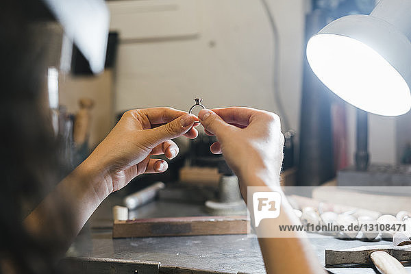 Geschorene Hände einer Handwerkerin  die in der Werkstatt einen Ring am Tisch hält