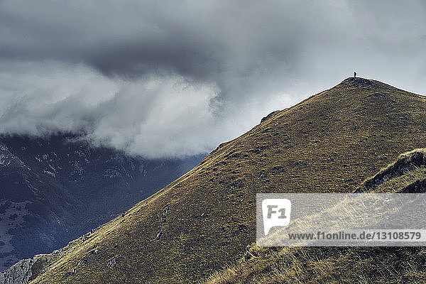 Distant view of man standing on Balkan Mountains against cloudy sky