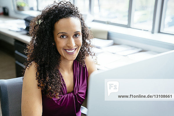 High angle portrait of businesswoman using desktop computer at desk in office