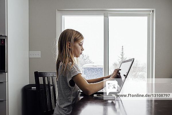 Seitenansicht eines Mädchens mit Laptop am Tisch
