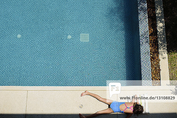 Overhead view of girl lying on poolside
