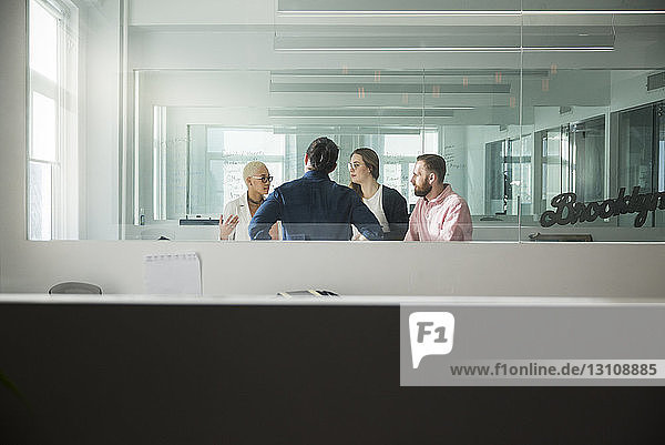 Business people discussing in office seen through window