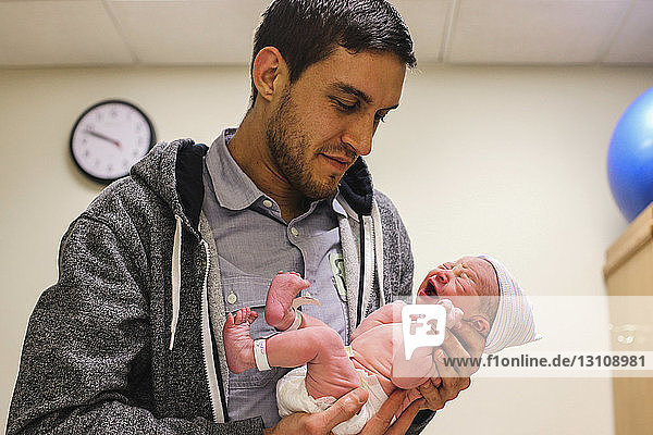 Father carrying newborn daughter while standing at hospital