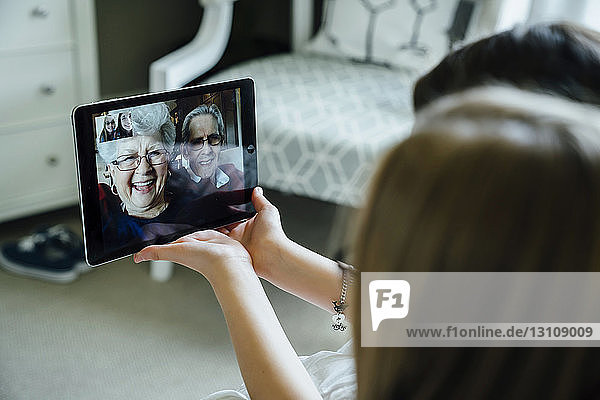 Sisters video conferencing with grandparents through tablet computer at home