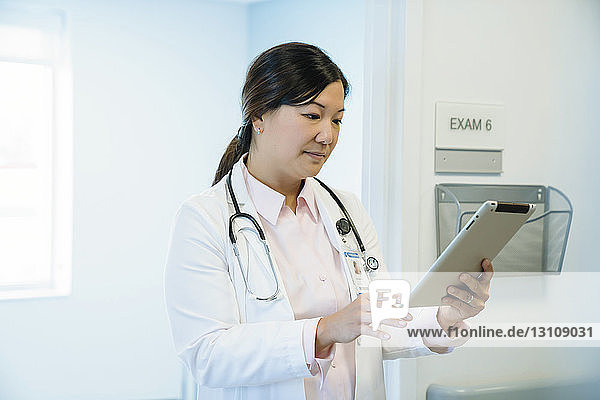Female doctor looking at tablet computer while standing in hospital corridor