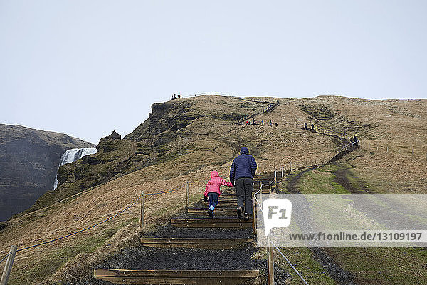 Rear view of father and daughter climbing steps on mountain