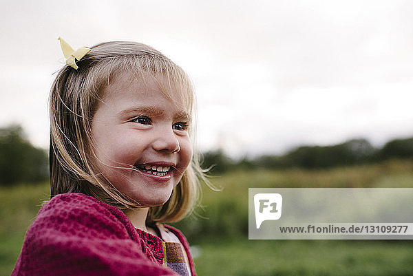 Fröhliches Mädchen schaut auf dem Feld im Park weg