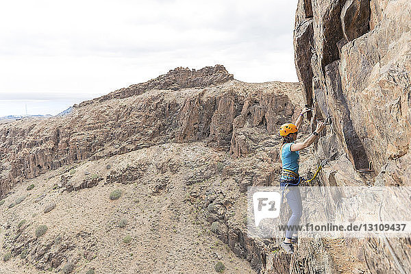 Weibliche Wanderin benutzt Sprossen beim Klettern an einer Felsformation