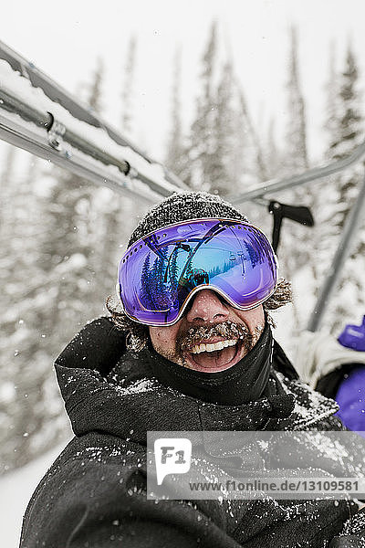 Cheerful man wearing ski goggles during winter