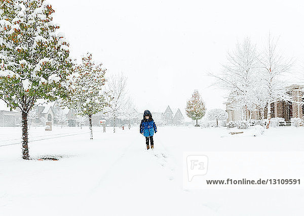 Junge geht bei nebligem Wetter auf schneebedeckter Straße
