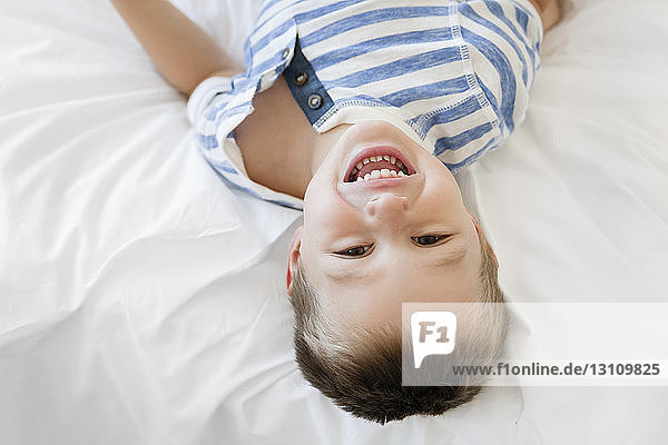 Portrait eines fröhlichen Jungen auf dem Bett liegend