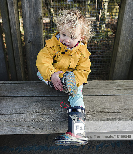 High angle view of girl looking away while sitting on wooden seat