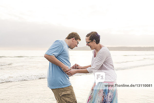 Seitenansicht eines fröhlichen  am Strand spielenden Paares