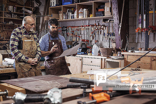 Handwerker besprechen Arbeit mit leitendem Mann im Stehen auf dem Workshop