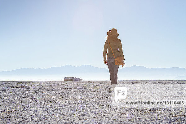 Rear view of woman walking on field against clear sky at Antelope Island