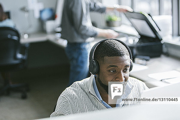 Hochwinkelansicht eines Geschäftsmannes am Desktop-Computer mit Kollegen im Hintergrund