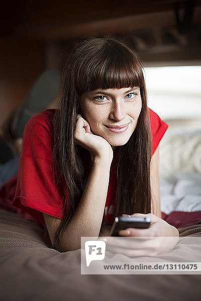 Porträt einer jungen Frau  die lächelnd auf dem Bett im Wohnmobil entspannt