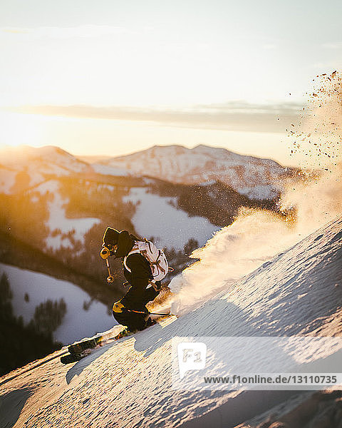 High angle view of man skiing on snow covered mountain against sky during sunset