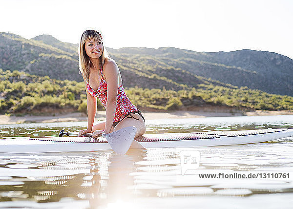 Lächelnde Frau schaut weg  während sie auf dem Paddelbrett in Bartlett Lake sitzt