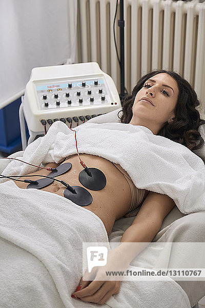 Hochwinkelansicht eines Patienten mit Elektroden Physiotherapie im Liegen in einer medizinischen Klinik