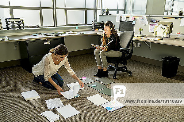 Businesswomen arranging documents on floor in office